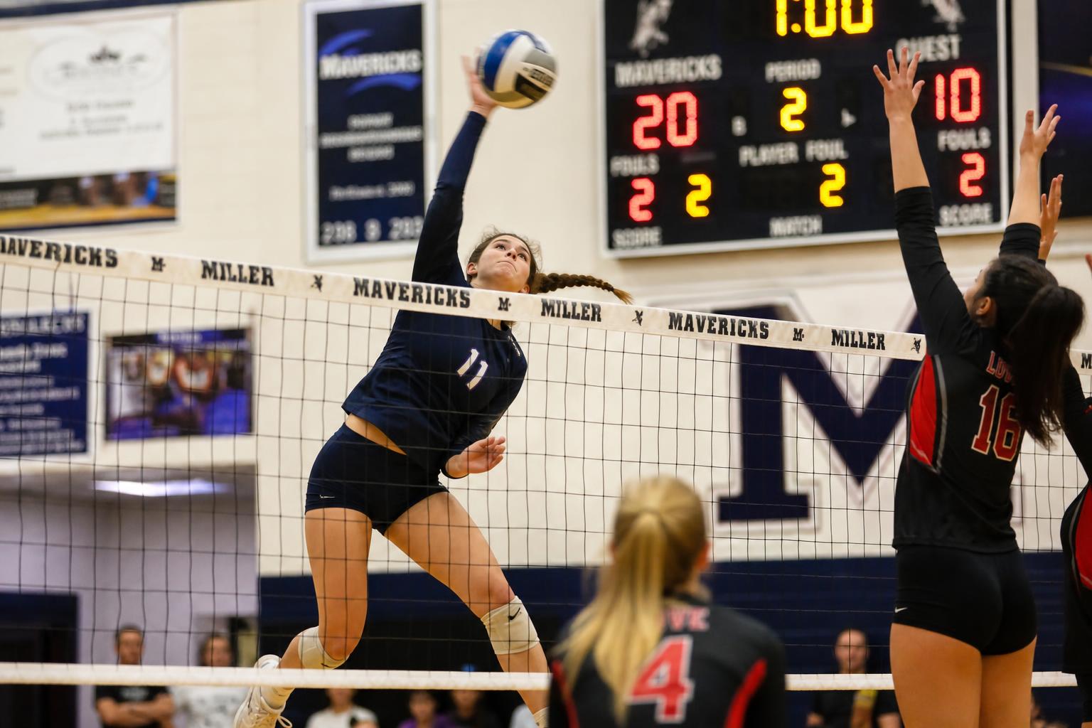 High school volleyball player spiking at the net
